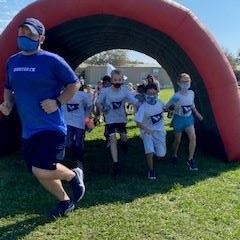 A Boosterthon representative and several students running through the Boosterthon tunnel. 