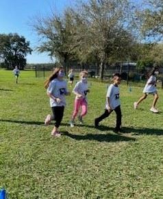 Four students in athletic wear running outside for the Fun Run.