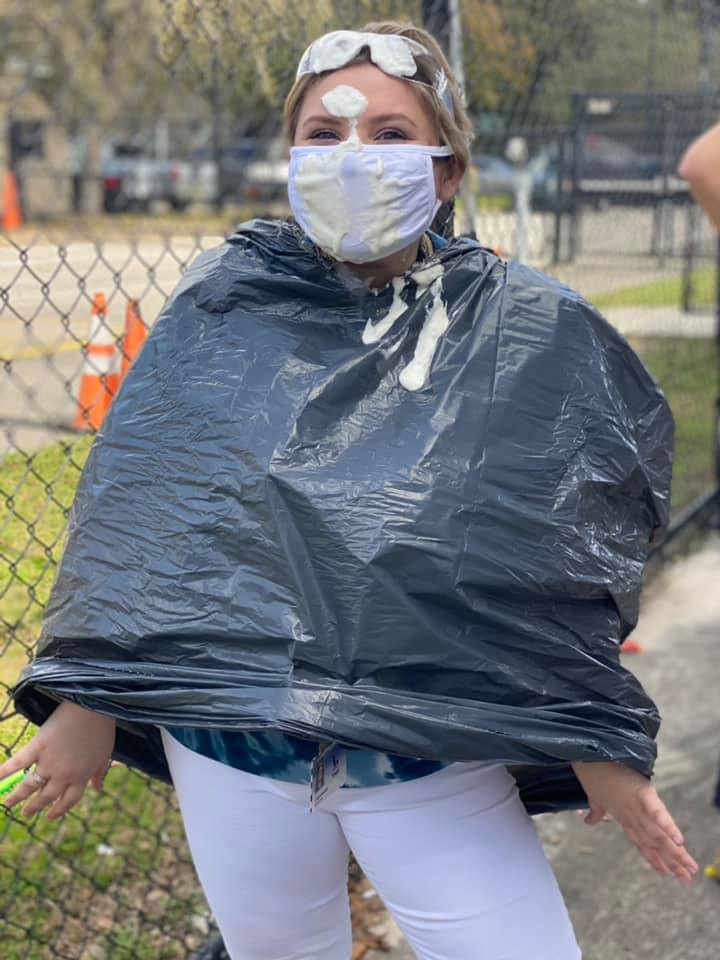 A female teacher wearing safety goggles and a garbage bag, covered in whipped cream!