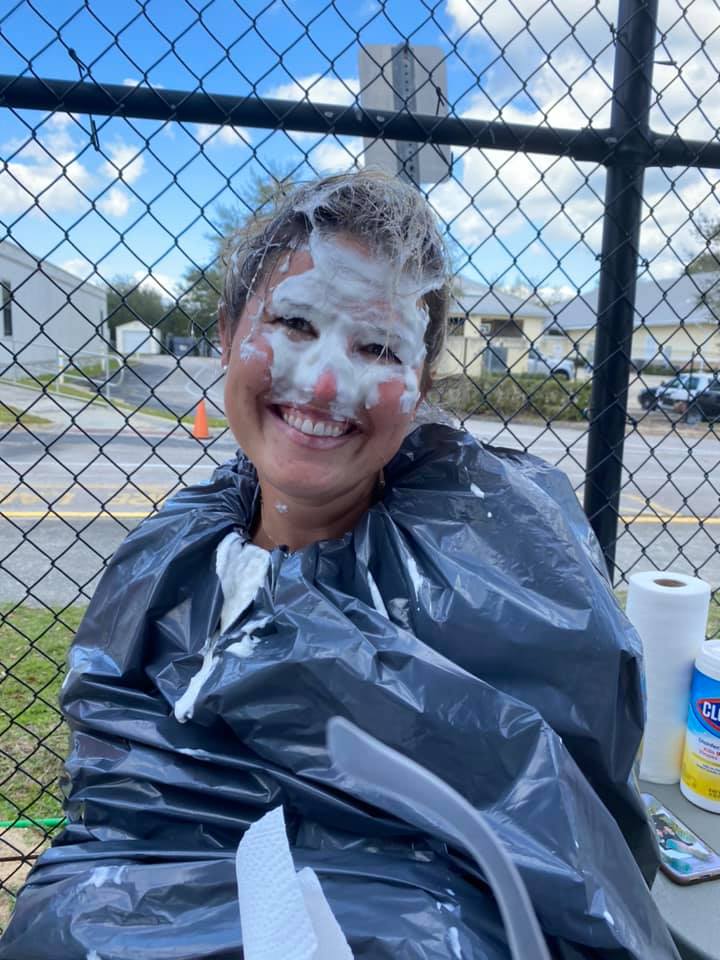 A female teacher wearing a garbage bag and covered in whipped cream from Pie Day!